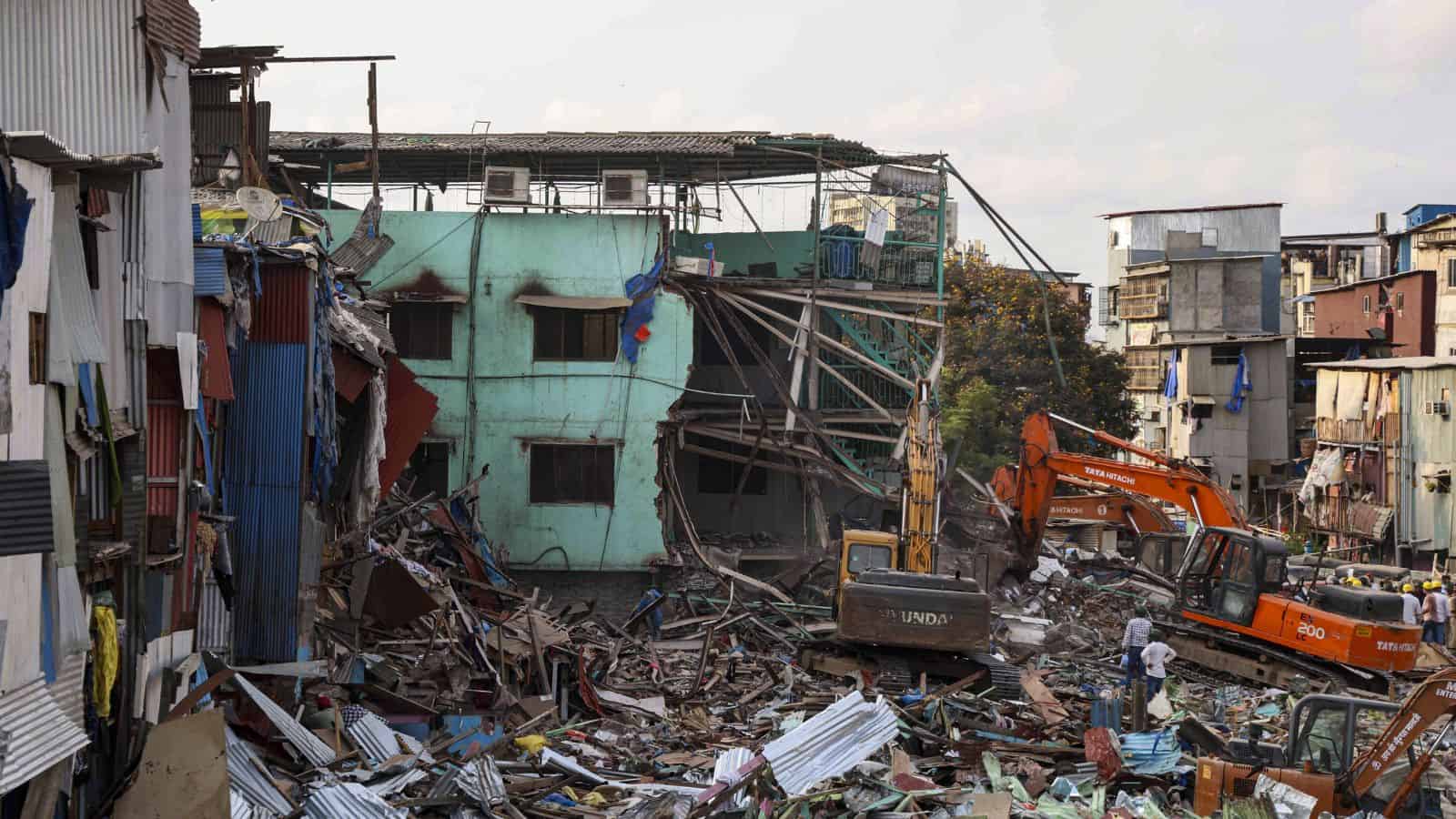Urban building collapse with rescue operations and heavy machinery in a densely populated area.