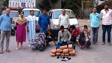 A woman and children collecting bricks on the street with men standing behind them in an urban setting.