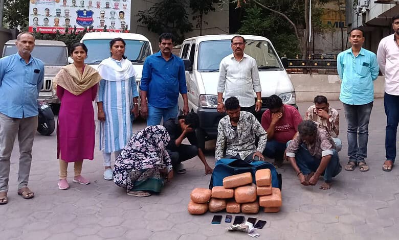 A woman and children collecting bricks on the street with men standing behind them in an urban setting.