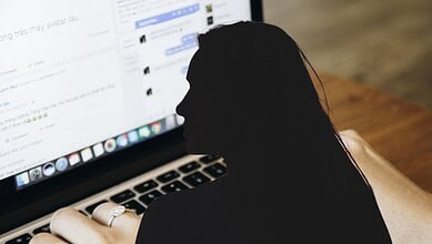 SEO-friendly ALT tag: Person working on a laptop with social media and messaging apps open on the screen.