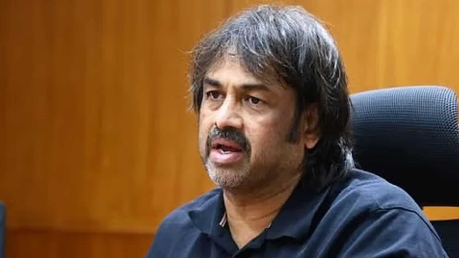 A man with dark hair and a beard speaking during a press conference or interview in an indoor setting.