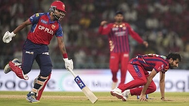 A cricket player in red and blue uniform running on the field during a match.