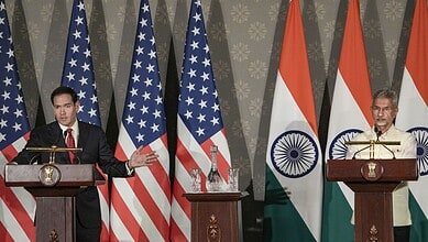 U.S. and Indian officials hold joint press conference with flags in the background.