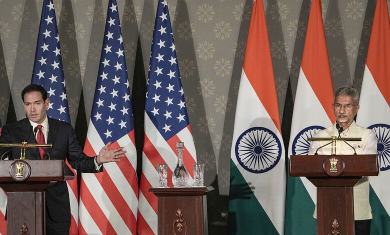U.S. and Indian officials hold joint press conference with flags in the background.