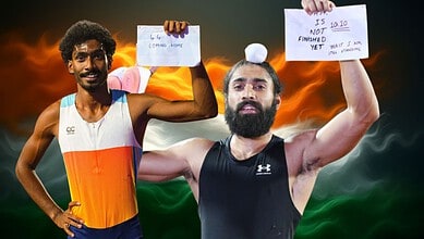 Two male athletes holding signs, celebrating victory with Indian flag in the background.