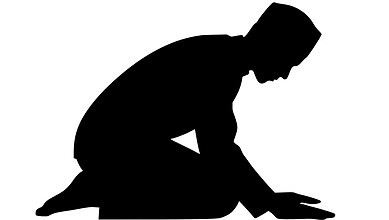 A man kneeling in prayer silhouette, symbolising devotion and spirituality.