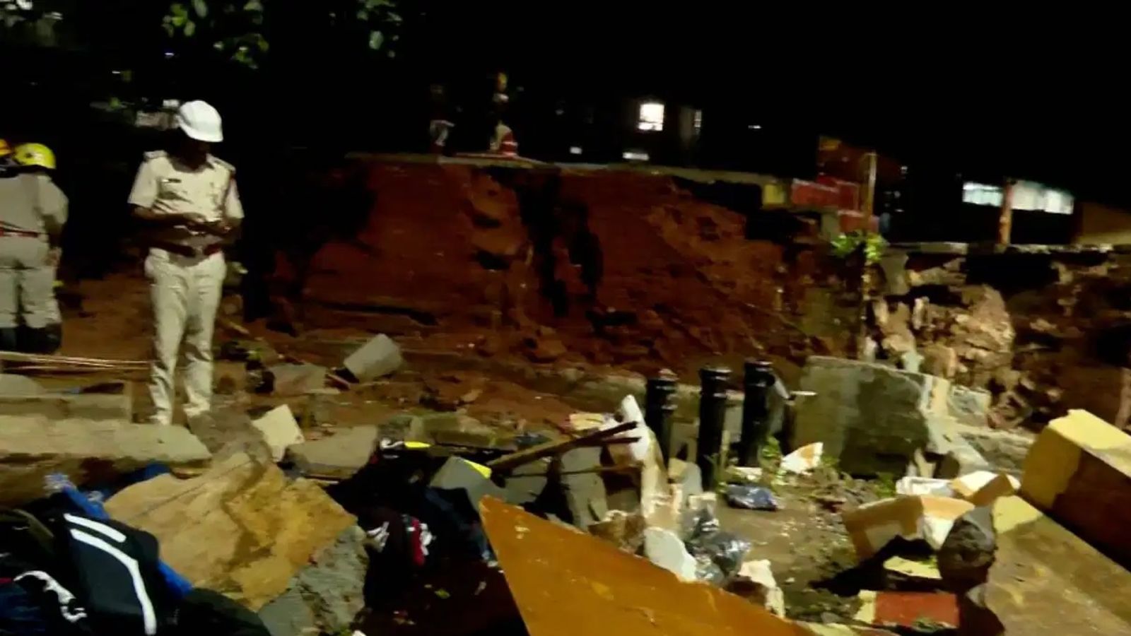 Construction site with workers and debris, safety helmets, and scattered materials in an outdoor environm.