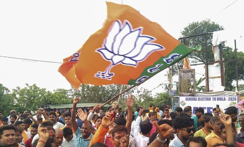 BJP party flag being waved during a political rally in India with a crowd of supporters.