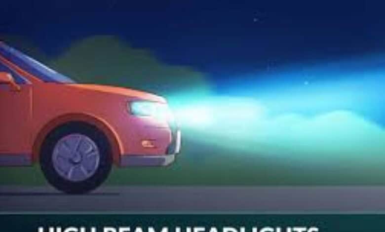 Bright red car with headlights on driving at night on a dark road.