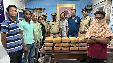 A group of police officers and civilians standing behind a table stacked with seized bricks of illegal su.