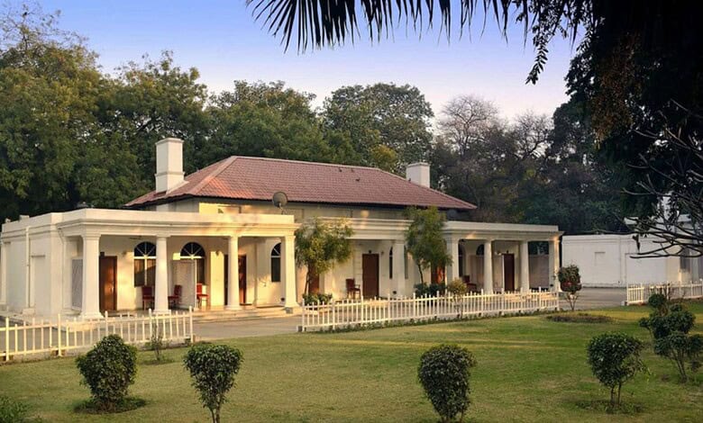 The Siasat Daily: Elegant colonial-style house with white walls, red roof, surrounded by lush greenery an.