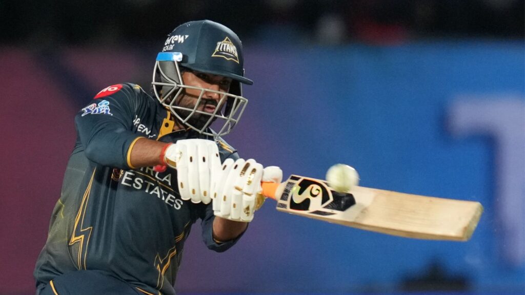 A cricket player in action hitting the ball with a bat during a match.