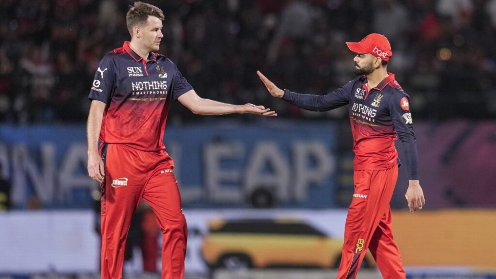 A cricket players in red uniforms exchanging a high-five on the field during a match.