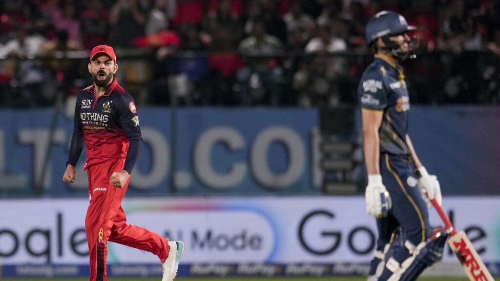 A cricket player in red and black uniform celebrating on the field during a match.