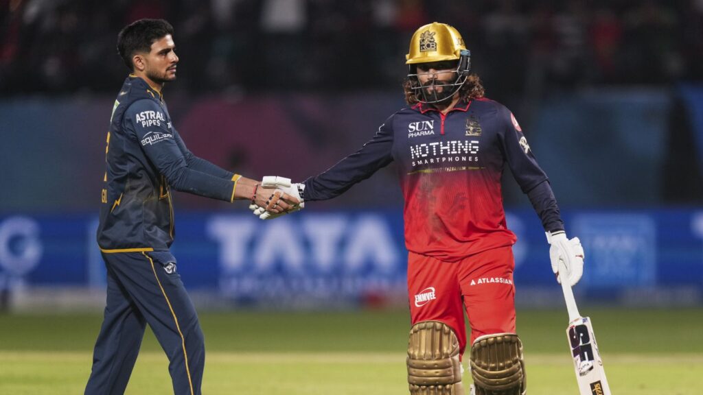 A young cricket player shaking hands with a wicketkeeper on the field during a match.
