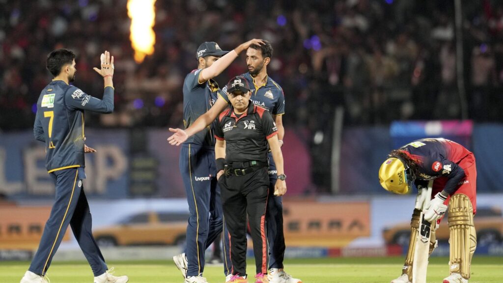 High-performance cricket players celebrating on the field during a match, with a wicketkeeper adjusting g.