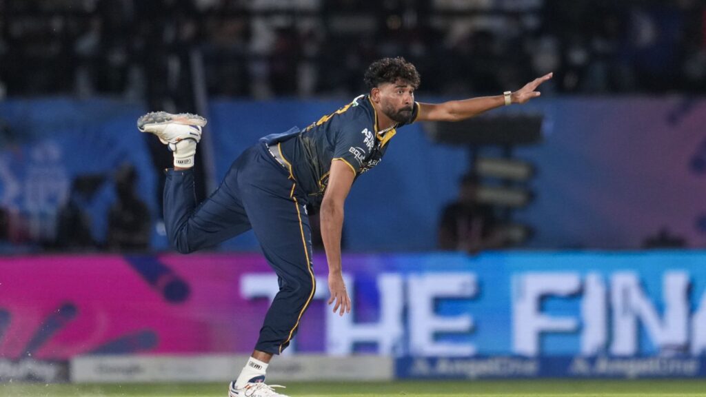 A cricket player diving to catch the ball on the field during a match.