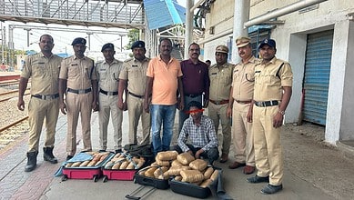 A man with a face mask surrounded by police officers displaying seized packages on the street.