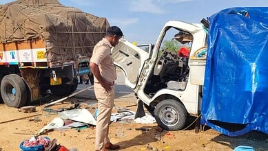 A man inspecting a small white truck involved in a road accident with debris scattered around.