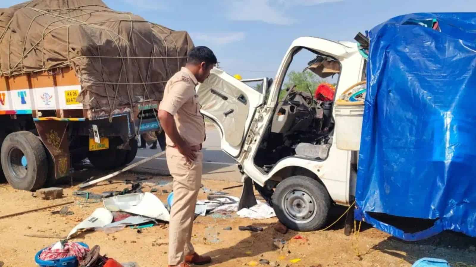 A man inspecting a small white truck involved in a road accident with debris scattered around.