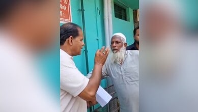 A man in white shirt engaging in a conversation with an elderly man with a white beard outside a colourfu.