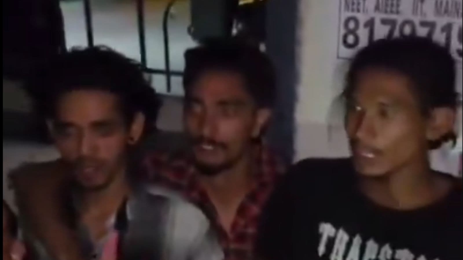 A young group of men standing together outdoors at night, engaging in conversation.