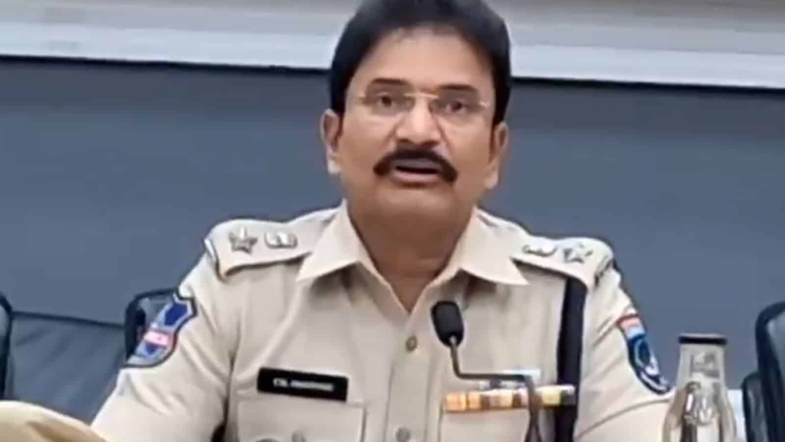 A police officer speaking at a press conference, wearing a beige uniform with badges and a microphone.