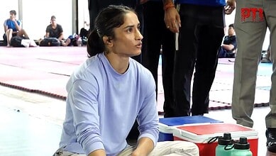 A woman in a light blue sports top sitting on the floor during a martial arts training session.
