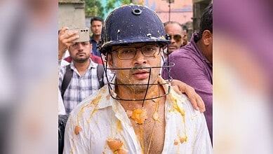 A man wearing a helmet and glasses, covered in orange powder, participating in a Holi celebration with a.