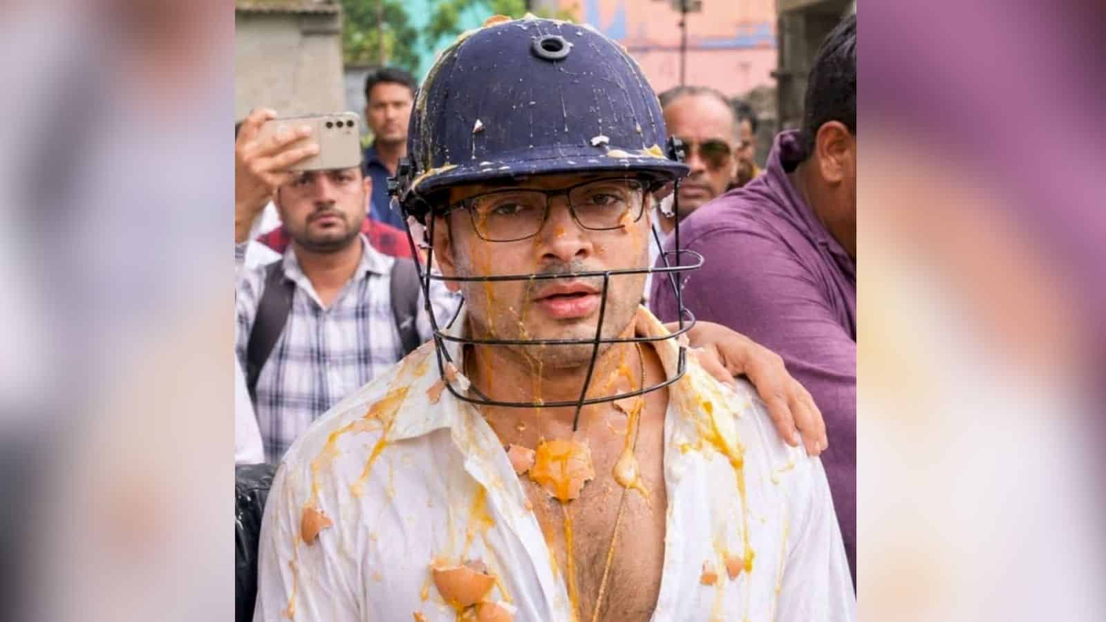 A man wearing a helmet and glasses, covered in orange powder, participating in a Holi celebration with a.