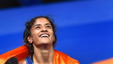 A woman smiling confidently with a vibrant orange scarf against a blue background, representing empowerme.
