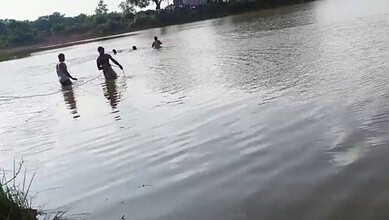 A woman and two children playing in a river, enjoying a sunny day outdoors.