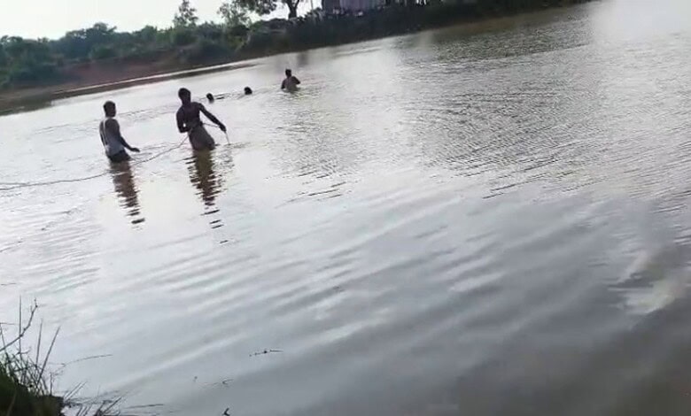 A woman and two children playing in a river, enjoying a sunny day outdoors.