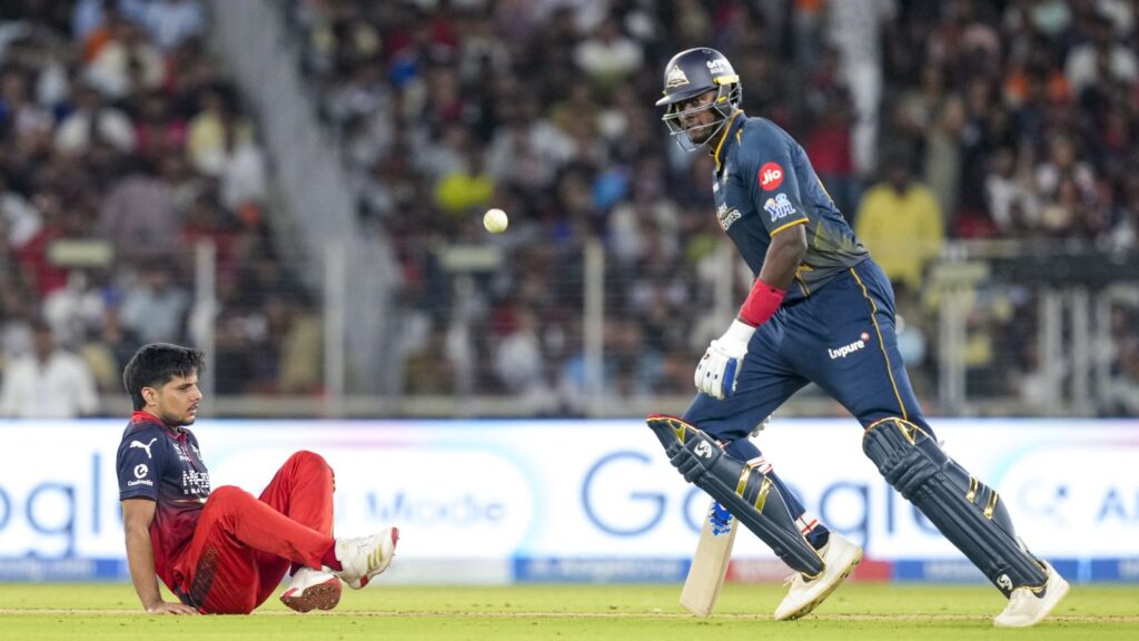 A cricket player in blue uniform running with the ball towards the stumps during a match.