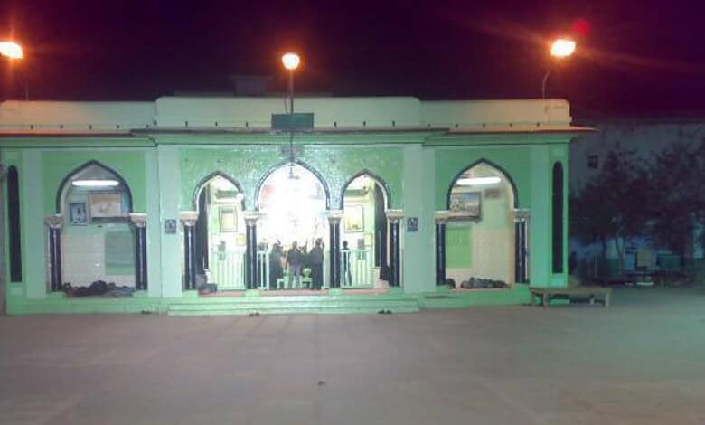 Bright green mosque entrance illuminated at night with arches and decorative elements, showcasing Islamic.