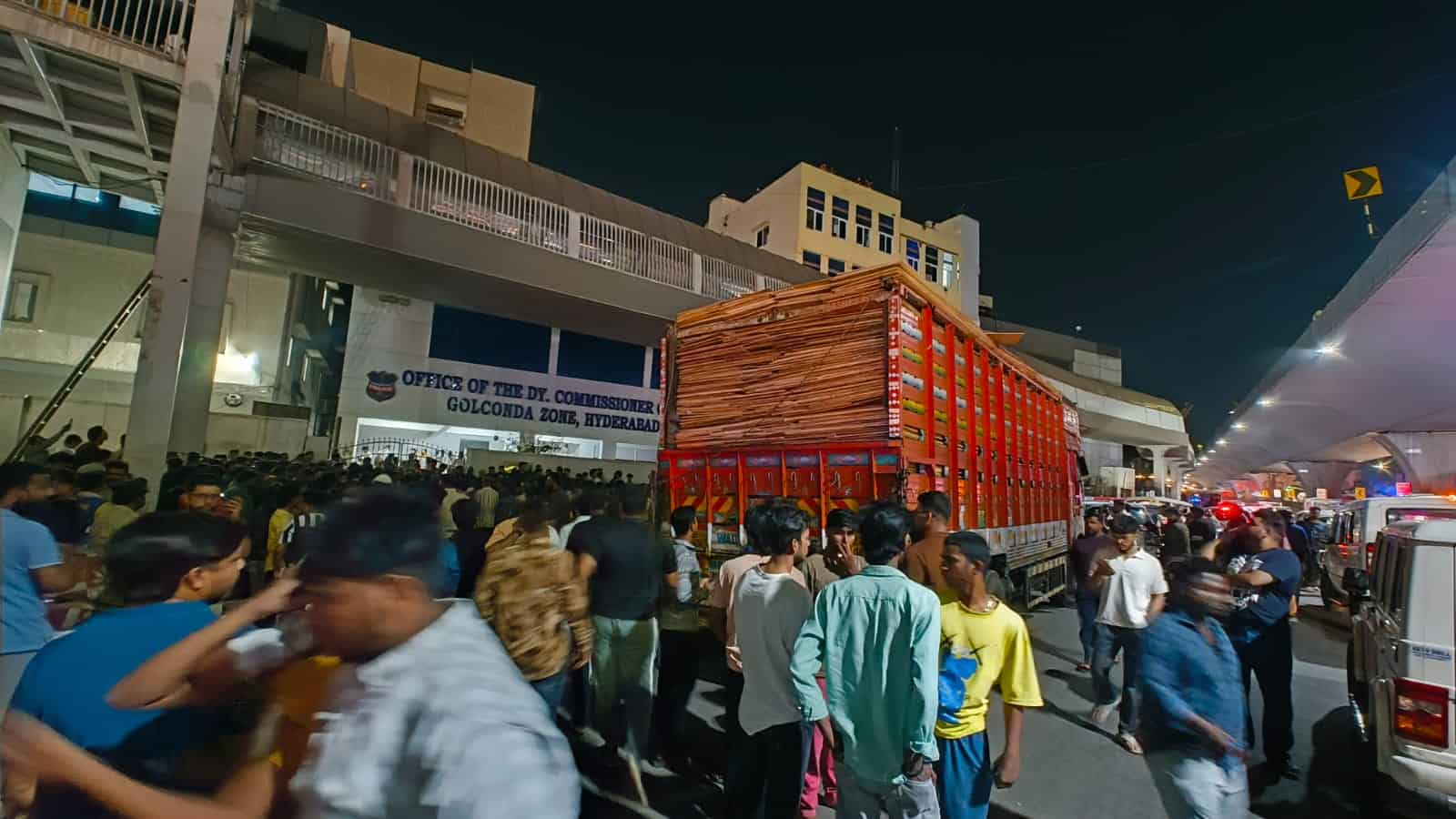 Crowd gathered around a container truck carrying cardboard outside the DCP Golconda Zone office in Hyderabad following stone pelting at Gudimalkapur.
