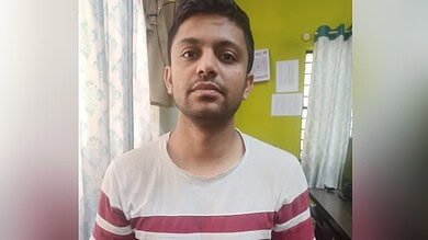 A young man with short dark hair and a neutral expression, wearing a white T-shirt with red stripes, stan.