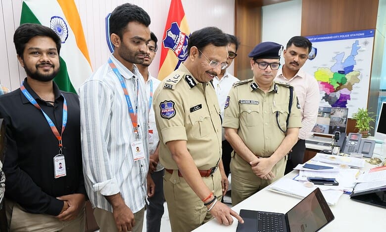 Police officers and civilians examining a laptop at a police station, with maps and flags in the backgrou.