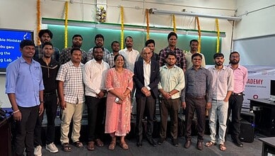 Group of university students and faculty members posing together at an academic event, with a green chalk.
