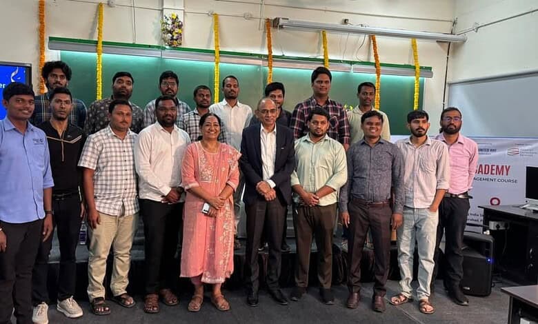 Group of university students and faculty members posing together at an academic event, with a green chalk.