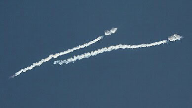 Image of missiles and drones flying in the sky amid Iran war tensions, with smoke trails visible.