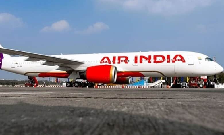 Air India commercial airplane parked on runway under blue sky with clouds.