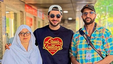 Aly Goni with his parents, smiling and dressed casually, before leaving for Haj pilgrimage, reflecting em.