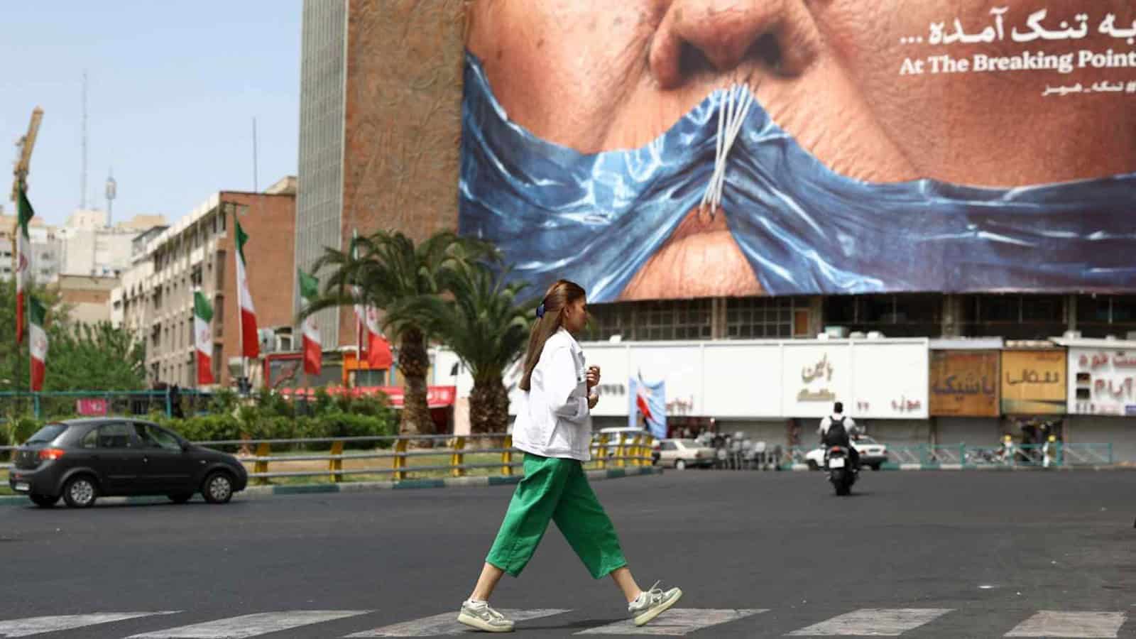 Protesters cover their mouths with a blue cloth in a busy city street amid US-Iran tensions over Hormuz.
