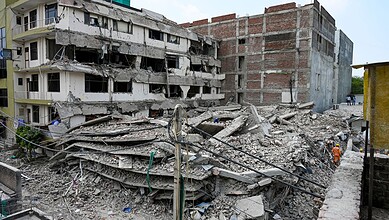 Building collapse aftermath in urban area, debris and damaged structures.