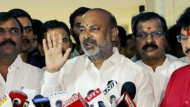 Prominent Indian politician speaking at a press conference surrounded by media microphones and supporters.