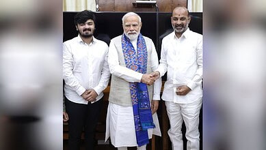 Indian Prime Minister Narendra Modi with two individuals, engaging in a handshake during a formal meeting.