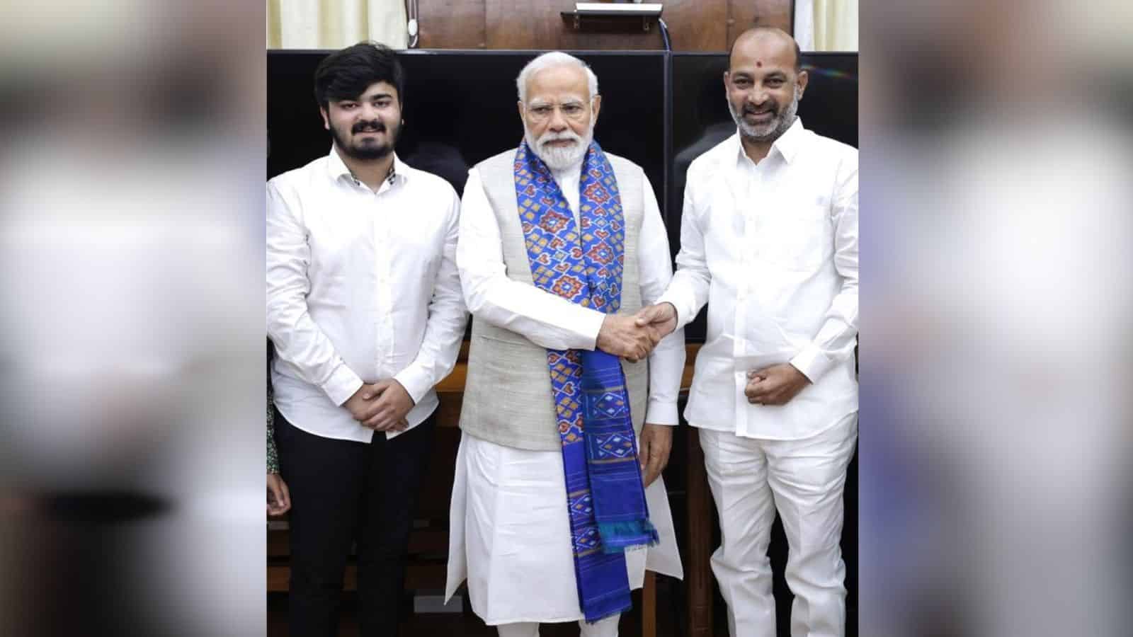 Indian Prime Minister Narendra Modi with two individuals, engaging in a handshake during a formal meeting.