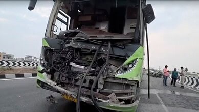 Damaged green bus after collision on highway with debris and injured passengers nearby.