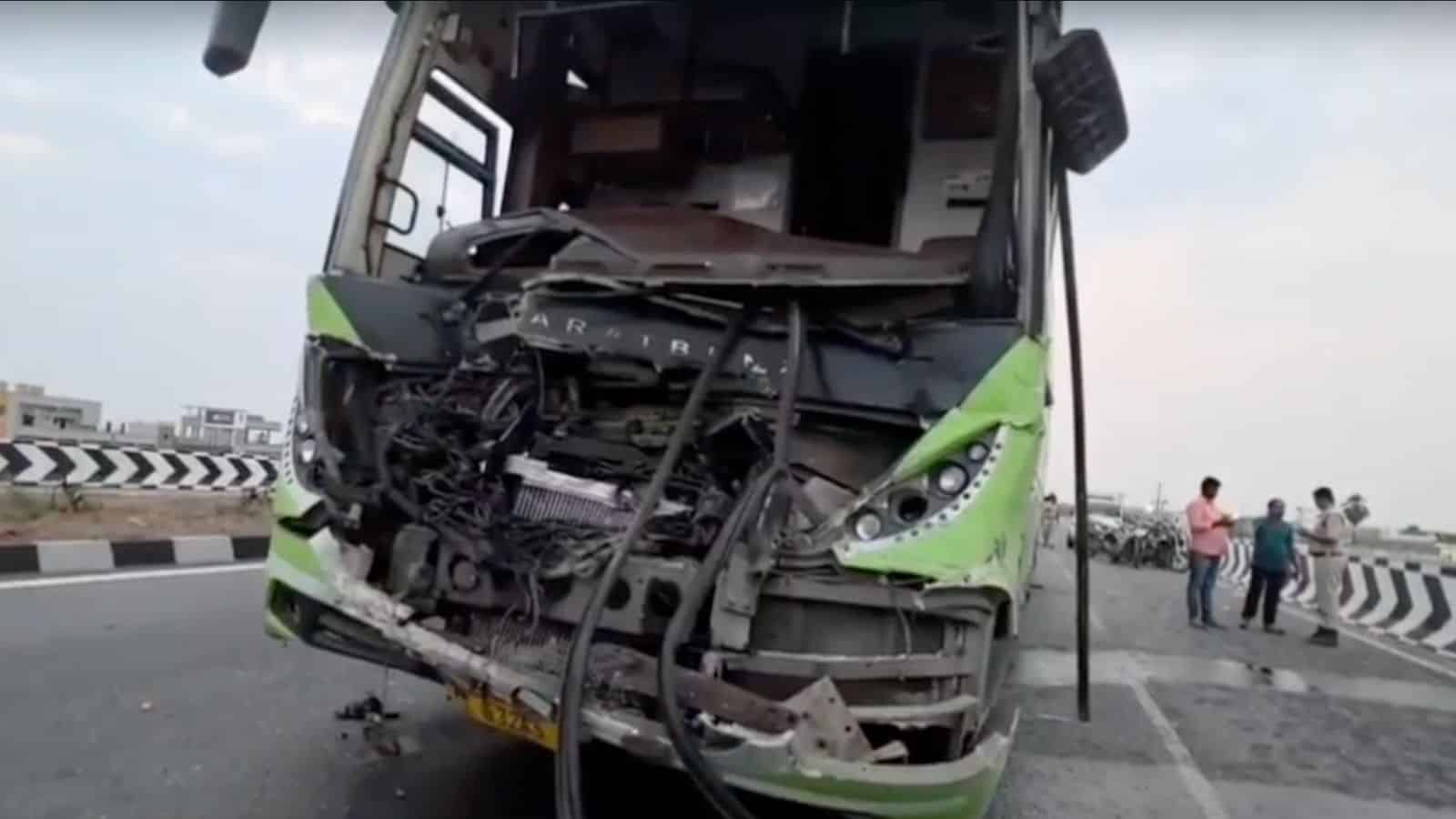 Damaged green bus after collision on highway with debris and injured passengers nearby.